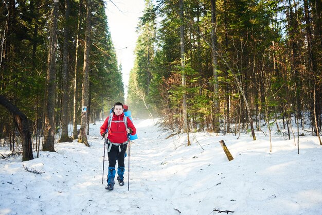 Male tourist goes on a ladder in the winter forest