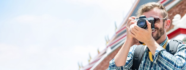 Male tourist photographer taking photo with camera while traveling in Bangkok Thailand