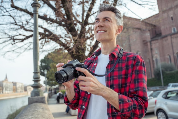 Male tourist in a plaid shirt with camera