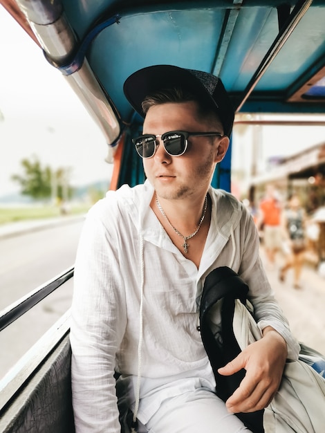 Male tourist rides a tuk tuk taxi, Phuket, Thailand