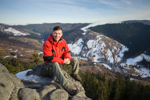 Male tourist sitting on rock on top of the mountain