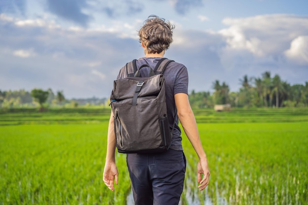 Мужчина-турист с рюкзаком идет по рисовому полю