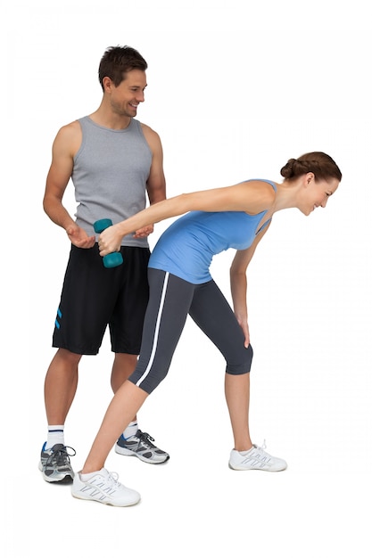 Male trainer assisting woman with dumbbell