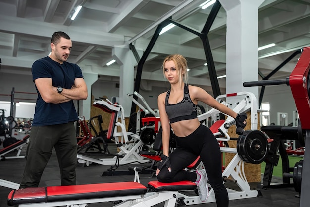 Male trainer help her woman client working with dumbbell weights at gym active lifestyle