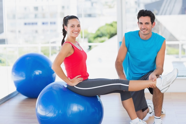 Male trainer helping woman with her exercises at gym