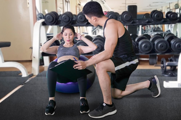 Photo male trainer teaching his client to sit up exercise