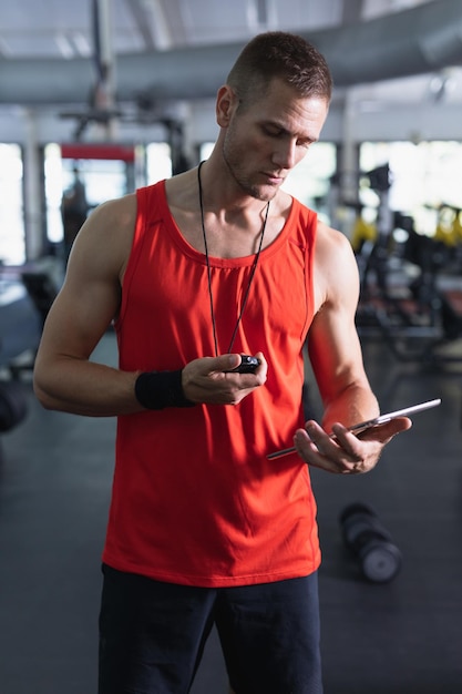 フィットネスセンターでデジタルタブレットを使用する男性トレーナー