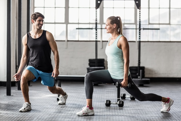 Male trainor with woman using dumbbells exercising 