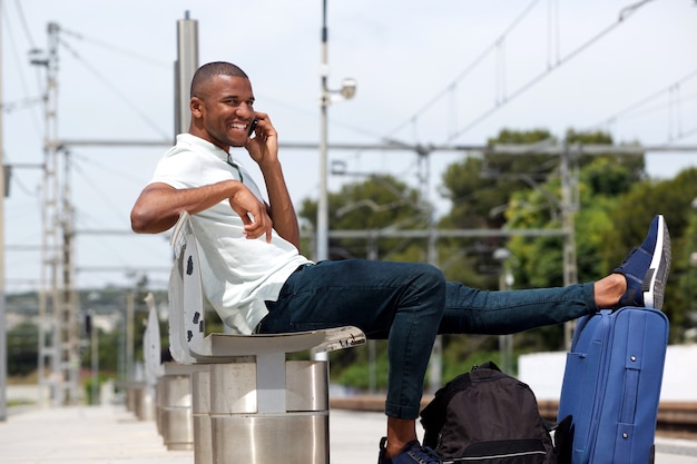 Мужчина-путешественник на вокзале с помощью мобильного телефона