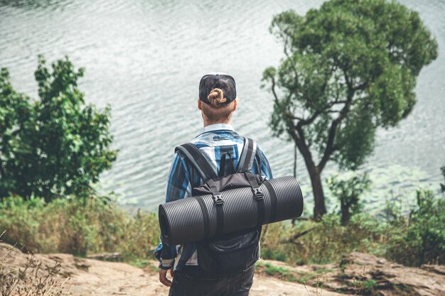 Photo male traveler with backpack and karimat in nature back view