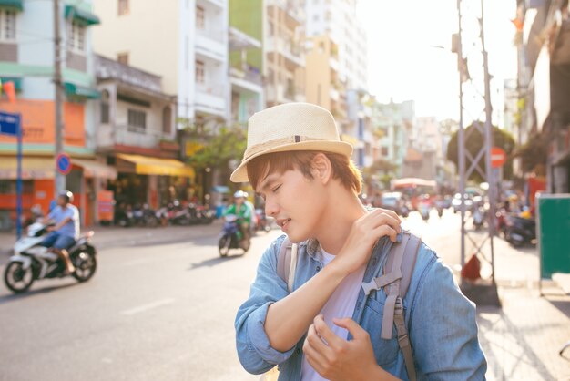 남성 여행자는 무거운 가방을 들고 긴 여행 후 피곤한 표정으로 보입니다.