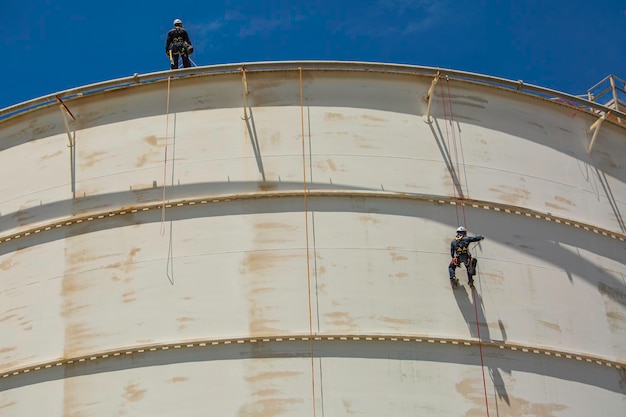 Male two worker down height tank roof rope access safety\
inspection thickness weld of storage tank gas