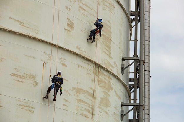 Male two worker inspection wearing safety first harness rope\
safety line working at a high place on tank roof spherical