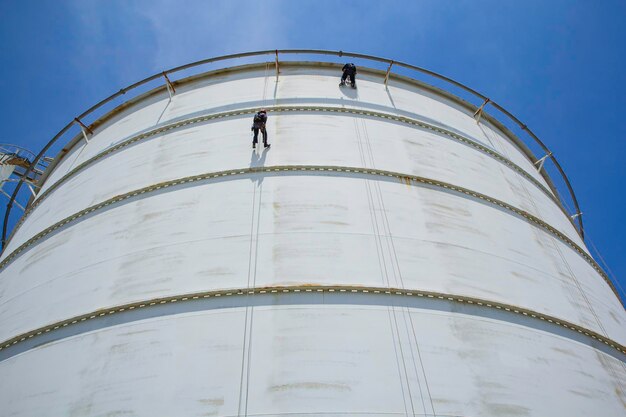 Male two worker rope access height safety inspection of\
thickness storage oil and gas tank industry