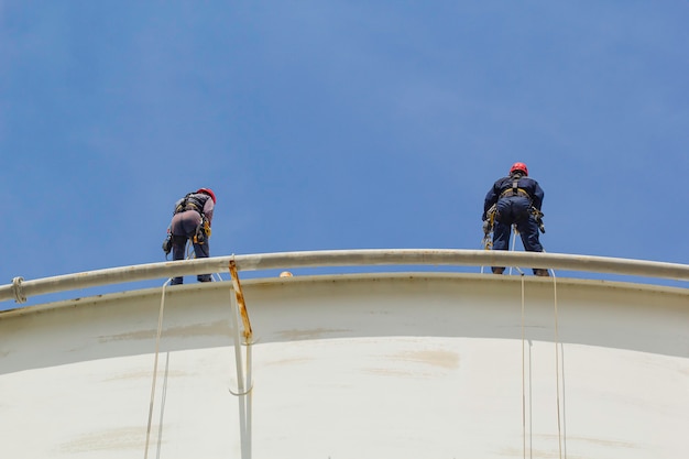 Male two worker rope access height safety inspection of thickness storage oil and gas tank industry