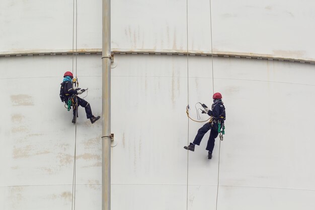Male two worker rope access  inspection of thickness storage  white tank industry