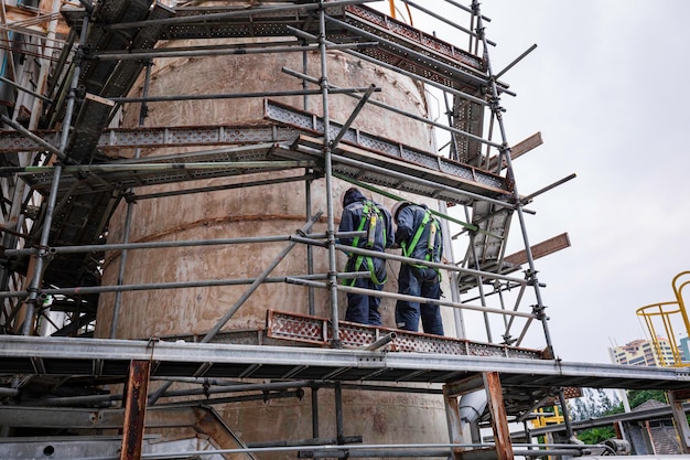 Male two worker wearing safety first harness and working at high scaffold