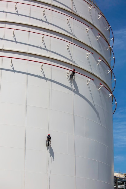 Male two workers control rope down height tank rope access\
inspection of thickness shell plate storage tank safety work at\
height.