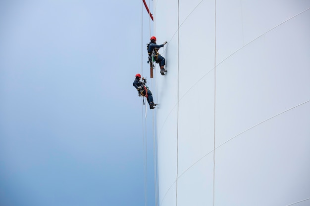 Male two workers down height tank rope access inspection of\
thickness shell plate storage tank gas propane safety work at\
height.