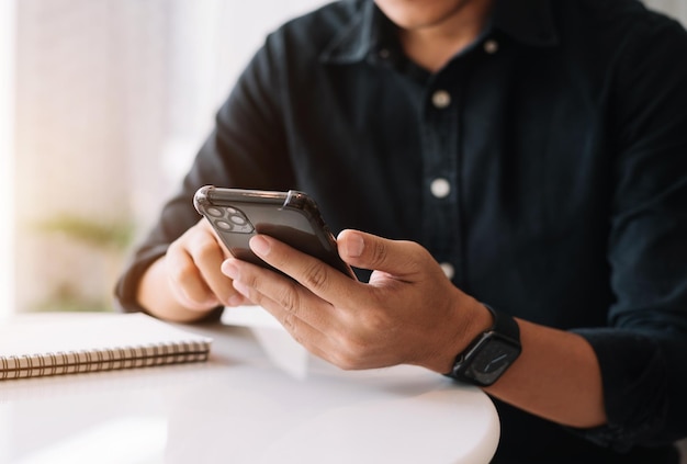 男性は朝のカフェでモバイル決済オンラインショッピングオムニチャネルにスマートフォンを使用します