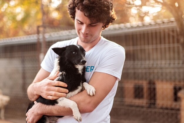 Male volunteer hugging dog in shelter