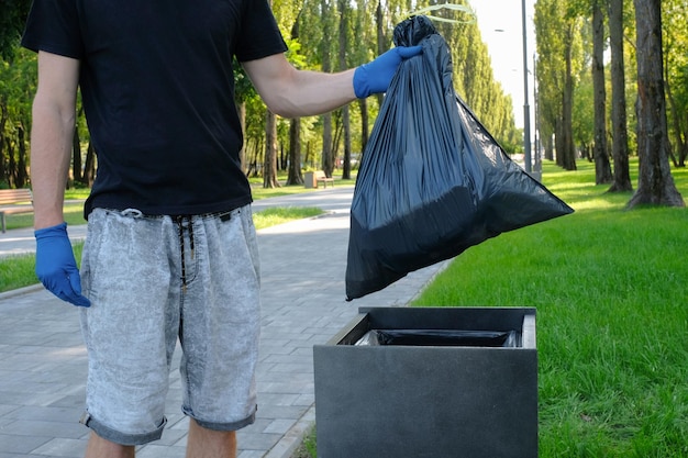 Foto un volontario maschio nel parco mette la spazzatura di plastica in una borsa