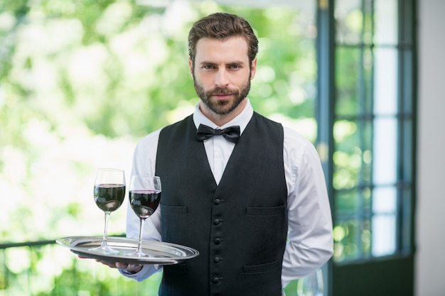 Male waiter holding tray with wine glasses