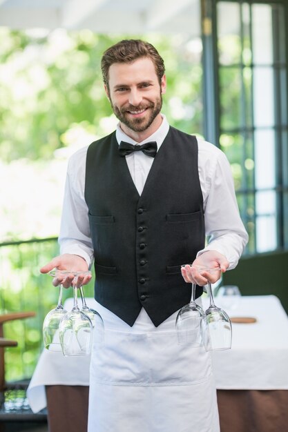 Male waiter holding wine glasses in the restaurant