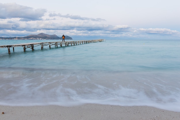 Male walking along a wooden pier and enjoy the view of the ocean