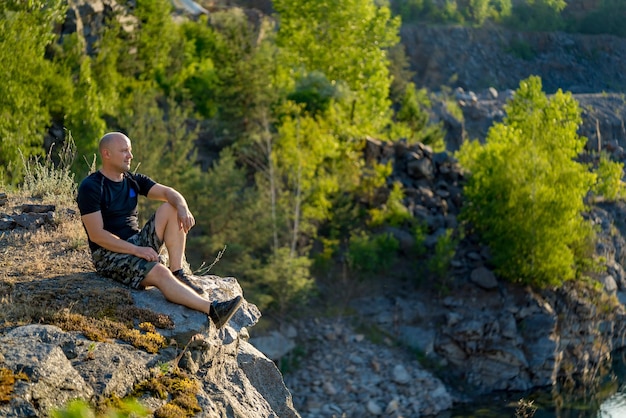 Male wanderer exploring wild land with high altitude in mountains. Man tourist with rucksack in nature environment for summer trekking during getaway discovering adventure.