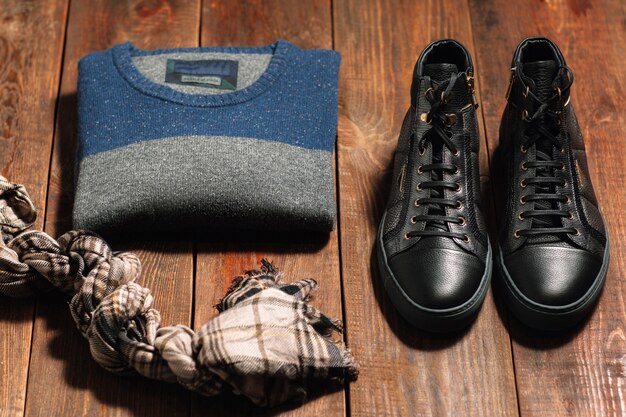 Male warm casual cloth set. Shoes pullover scarf on wooden desk.