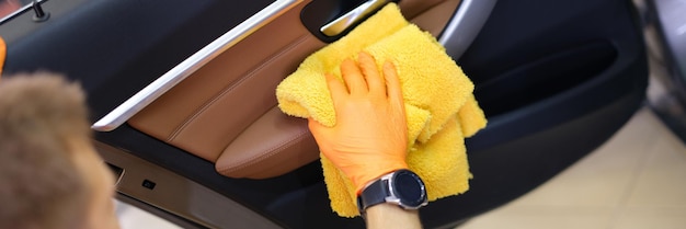 Male washer in gloves wipes car door with microfiber closeup