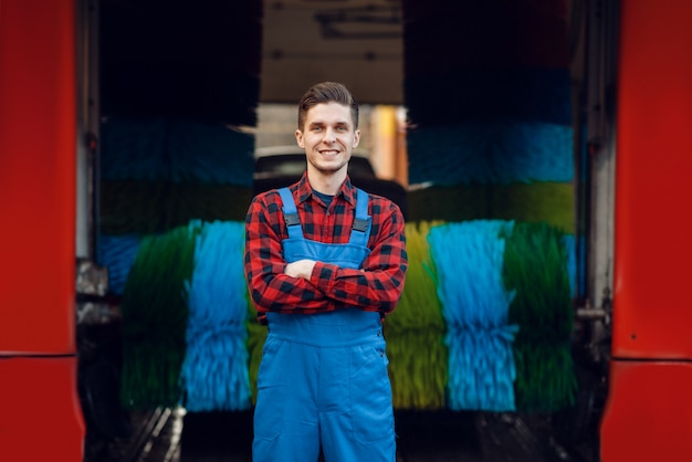 Photo male washer in uniform on automatic car wash with colorful brush