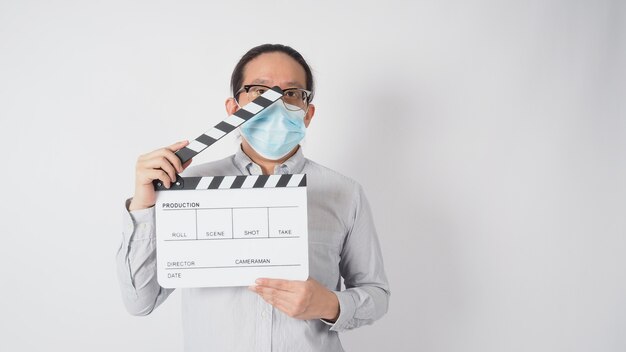 Male wear shirt and face mask and hand hold clapper board or movie slate. it use in video production and cinema industry on white background.