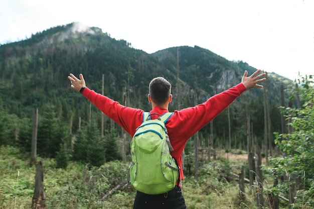 Male with a backpack stands against the beautiful landscape