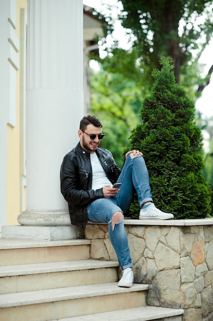 Мужчина с бородой в повседневной одежде читает сообщение со своего телефона