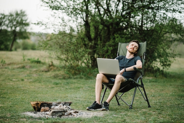 Il maschio lavora in remoto sul computer portatile mentre si gode la natura