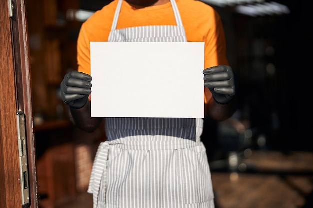 Foto lavoratore maschio in grembiule che tiene modello di carta in bianco