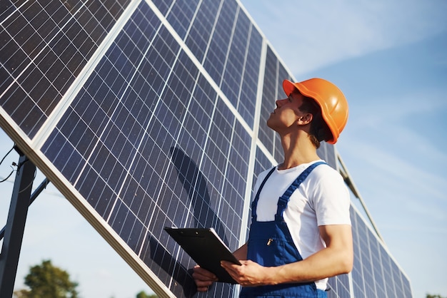 晴れた日に太陽電池で屋外の青い制服を着た男性労働者。