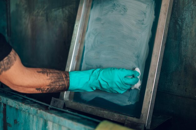 Male worker cleaning screen frame with a cloth in a printing
workshop