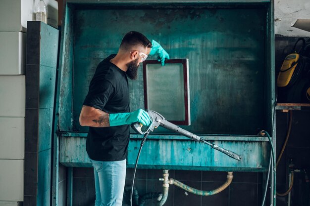 Male worker cleaning screen frame with water in a printing\
workshop