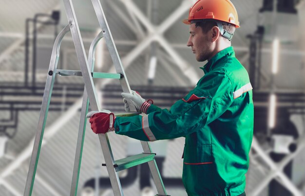 A male worker on construction site holding and carrying the ladder