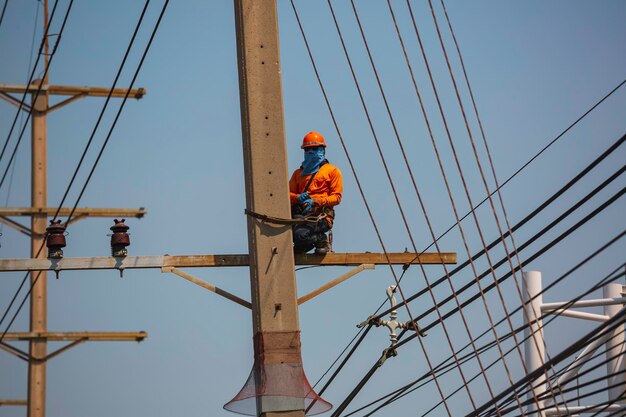 The male worker crane cable car repairs the electric pole and growing around power lines