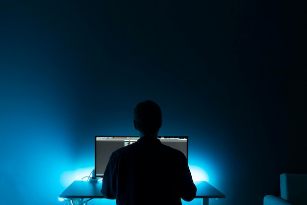 A male worker doing job on computer late in the night at home