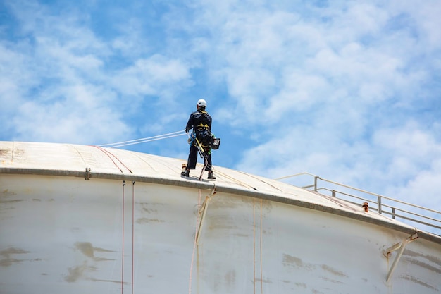 Male worker down height tank roof rope access safety inspection thickness weld of storage tank