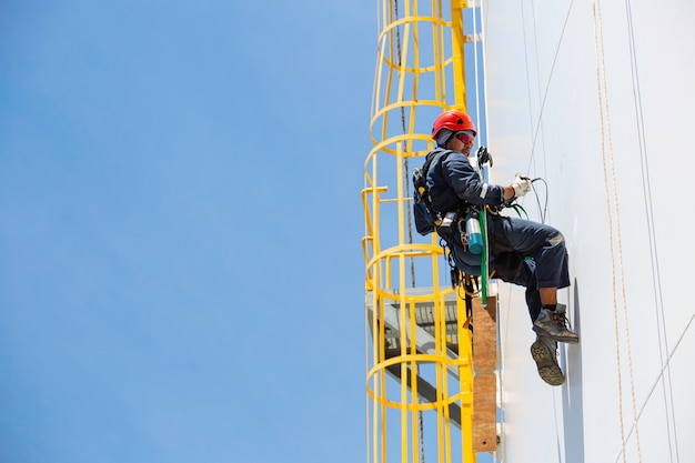 Photo male worker down height tank shell plate rope ladder  access safety inspection of thickness storage tank gas propane.