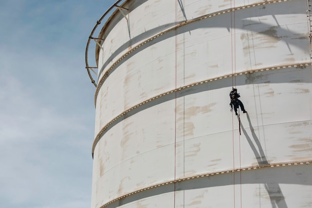 Male worker down height tank shell plate rope ladder access safety inspection of thickness storage tank