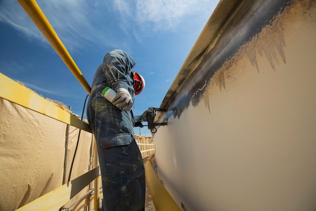 磁場試験の高試験鋼タンク突合せ溶接オーバーレイ炭素シェルプレートの貯蔵タンク油背景白コントラストの男性労働者