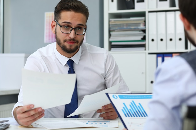 Male worker holding documents in hands in office