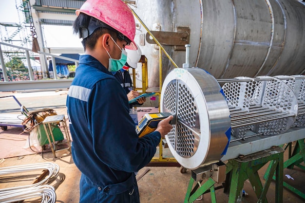 Male worker inspecting surface on heat exchanger tube bundle industrial construction warehouse positive